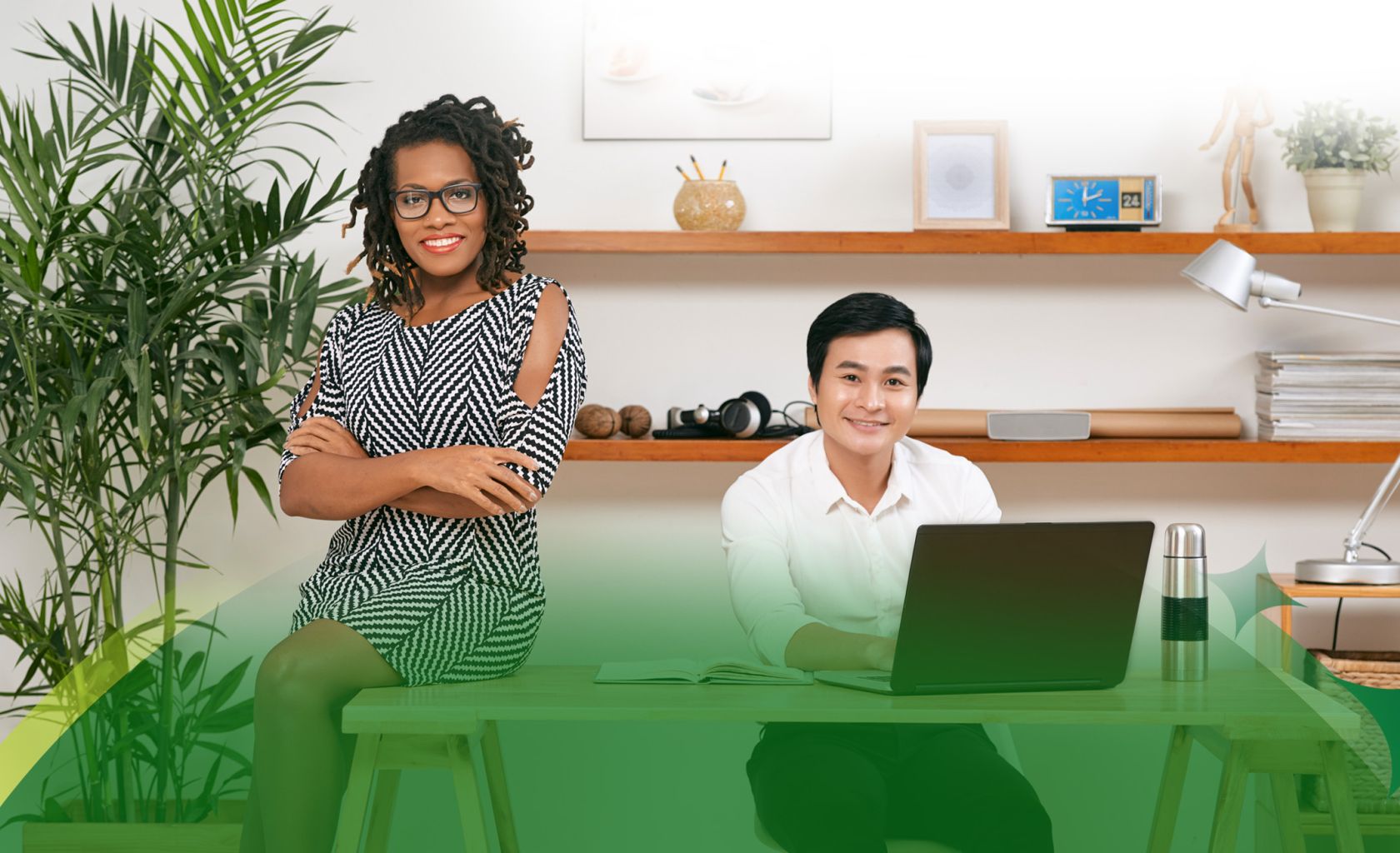 left to right woman setting on desk in black dress, man seeing at desk on computer